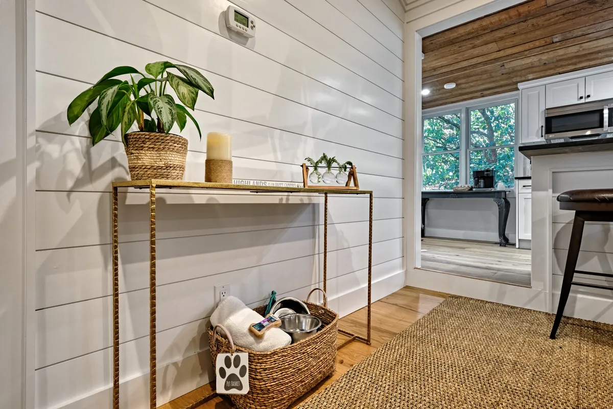 A welcoming entryway featuring a console table adorned with a plant, basket of supplies, and a candle. The space is bathed in warm lighting, creating an inviting and cozy atmosphere that sets the tone for the stay.