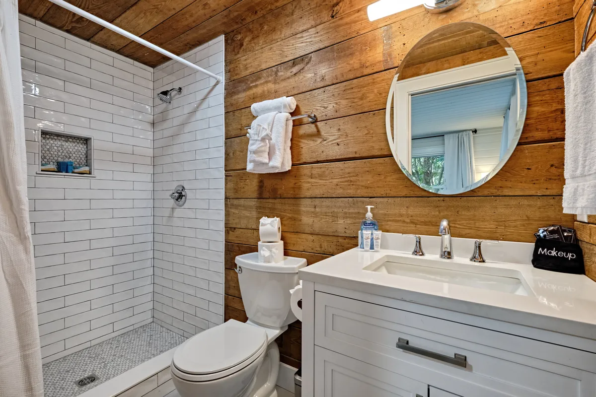 An inviting ensuite bathroom with a wooden accent wall, a modern shower area, and a well-lit vanity mirror. The scene conveys a sense of relaxation and rejuvenation for self-care routines.