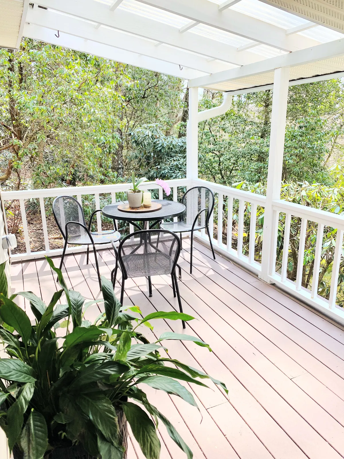 Another tranquil exterior shot of a patio table with surrounding chairs, lush greenery, and a potted plant. This setup hints at opportunities for casual dining, sunrise coffee rituals, and relaxed conversation, seamlessly connecting indoor culinary experiences to the natural surroundings.