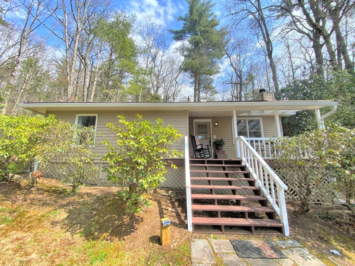 A welcoming front porch with stairs, rocking chair, and well-tended landscaping. The mood is serene and inviting, ideal for relaxing, connecting with nature, or spending time with your dog before or after a trail walk.